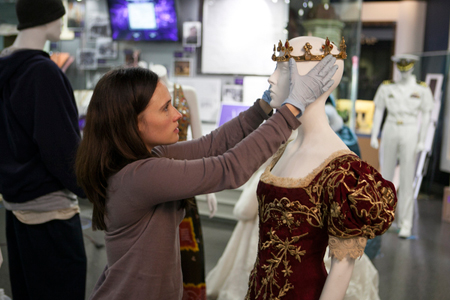 A curator at the “NBCUniversal Experience,” an attraction at Universal Studios Hollywood featuring never-before-seen props and priceless Hollywood artifacts from Universal Pictures and Focus Features, works to complete the display of an ensemble worn by Kristin Stewart in Snow White and The Huntsman. 